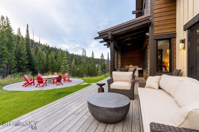 deck with an outdoor living space with a fire pit, a forest view, and a yard