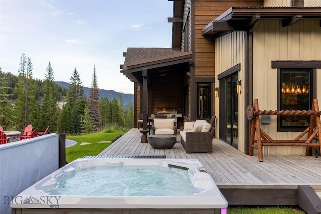 wooden deck with a hot tub, a mountain view, and a forest view