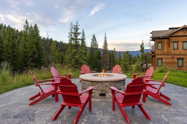 view of patio / terrace featuring an outdoor fire pit and a view of trees