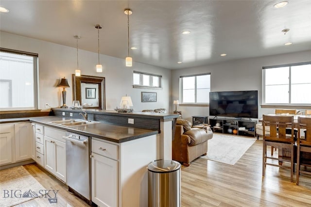 33 Intrepid Dr, Bozeman, MT 59718 - kitchen featuring dishwasher, a sink, light wood finished floors, a peninsula, and dark countertops