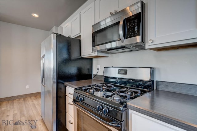 33 Intrepid Dr, Bozeman, MT 59718 - kitchen featuring appliances with stainless steel finishes, dark countertops, white cabinets, light wood-style floors, and recessed lighting