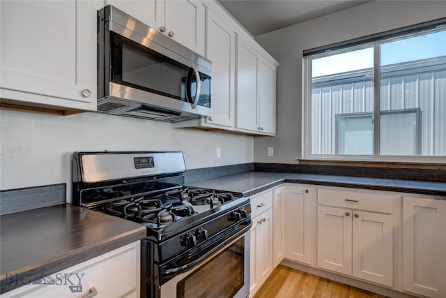 33 Intrepid Dr, Bozeman, MT 59718 - kitchen with stainless steel appliances, dark countertops, white cabinetry, and light wood-style floors