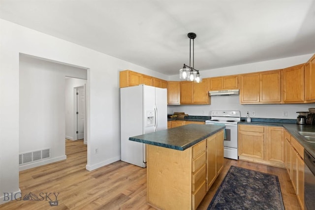 108 10th St Unit B, Belgrade, MT 59714 - kitchen with white appliances, dark countertops, under cabinet range hood, a center island, and light wood-style floors
