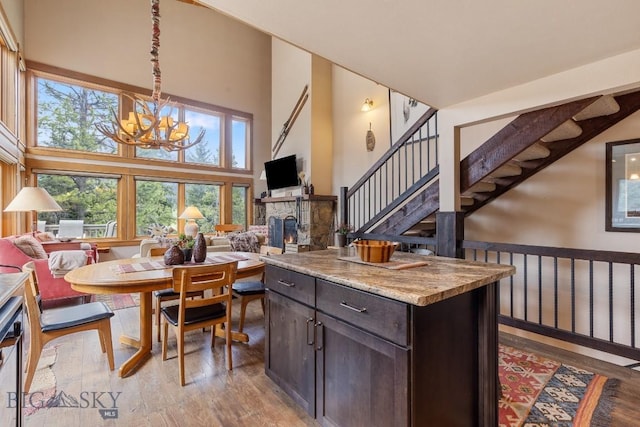 75 Rose Hip Cir, Big Sky, MT 59716 - kitchen with a chandelier, dark brown cabinetry, light wood finished floors, open floor plan, and a stone fireplace