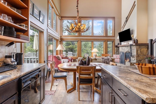 75 Rose Hip Cir, Big Sky, MT 59716 - dining area with a towering ceiling, a stone fireplace, a chandelier, and light wood-type flooring
