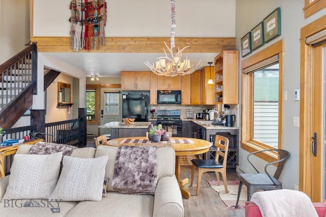 75 Rose Hip Cir, Big Sky, MT 59716 - kitchen with black appliances, wood finished floors, a chandelier, light countertops, and a center island