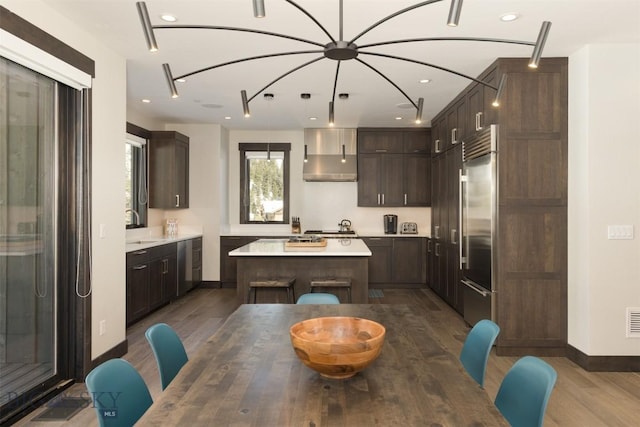 453 Outlook Trl, Big Sky, MT 59716 - kitchen featuring appliances with stainless steel finishes, wood finished floors, wall chimney range hood, a kitchen island, and dark brown cabinetry