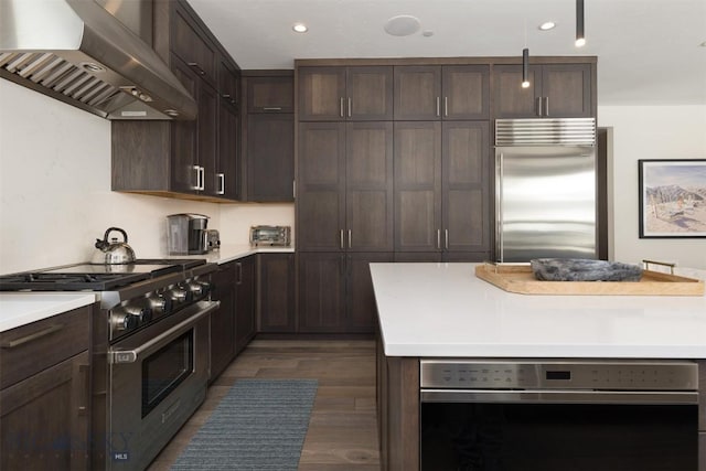 453 Outlook Trl, Big Sky, MT 59716 - kitchen featuring high quality appliances, wall chimney range hood, dark brown cabinets, dark wood-style floors, and light countertops