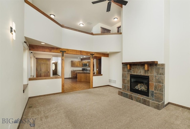 20 Prairie Grass B, Bozeman, MT 59718 - unfurnished living room with carpet, a tiled fireplace, a ceiling fan, and high vaulted ceiling