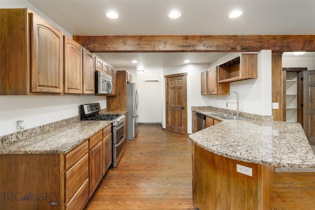 20 Prairie Grass B, Bozeman, MT 59718 - kitchen featuring appliances with stainless steel finishes, a peninsula, wood finished floors, light stone countertops, and recessed lighting