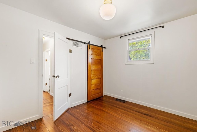 209 N 3rd, Bozeman, MT 59715 - unfurnished bedroom with dark wood-type flooring, a barn door, and baseboards