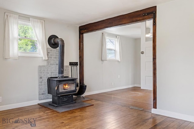 209 N 3rd, Bozeman, MT 59715 - unfurnished living room featuring a wood stove, wood-type flooring, beam ceiling, and baseboards