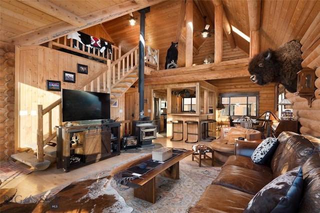 198 E River Rd, Emigrant, MT 59027 - living room featuring log walls, high vaulted ceiling, wood ceiling with exposed beams, a wood stove, and wood finished floors