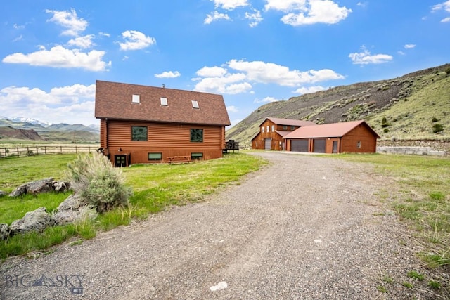 198 E River Rd, Emigrant, MT 59027 - view of home's exterior featuring a mountain view, an outbuilding, driveway, log exterior, and a view of rural / pastoral area