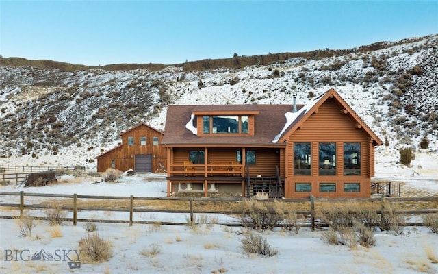 198 E River Rd, Emigrant, MT 59027 - snow covered rear of property with log siding, a detached garage, a porch, and roof with shingles