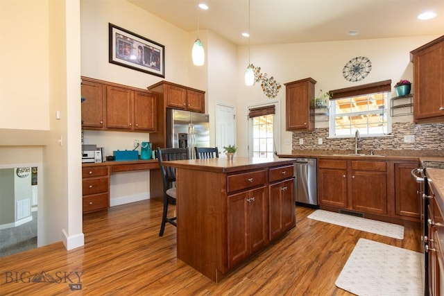 2008 Avocet Ct, Belgrade, MT 59714 - kitchen with appliances with stainless steel finishes, a sink, dark wood-type flooring, a kitchen bar, and a towering ceiling