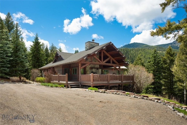 250 Petes Way, Big Sky, MT 59730 - view of front of house featuring a wooded view, a chimney, and a deck with mountain view
