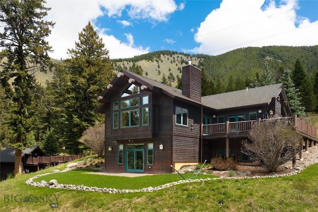 250 Petes Way, Big Sky, MT 59730 - rear view of property featuring a chimney, french doors, a yard, a view of trees, and a deck with mountain view