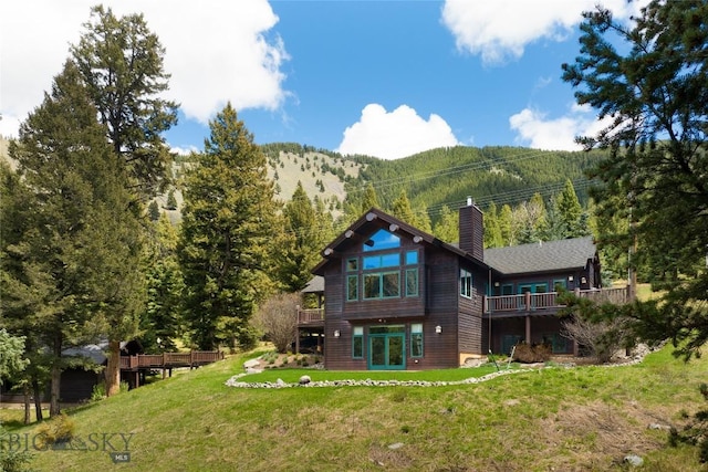 250 Petes Way, Big Sky, MT 59730 - rear view of house featuring a chimney, a lawn, and a deck with mountain view