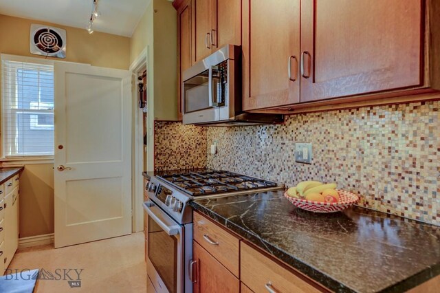 923 W Clark St, Livingston, MT 59047 - kitchen featuring appliances with stainless steel finishes, backsplash, dark stone countertops, and brown cabinets