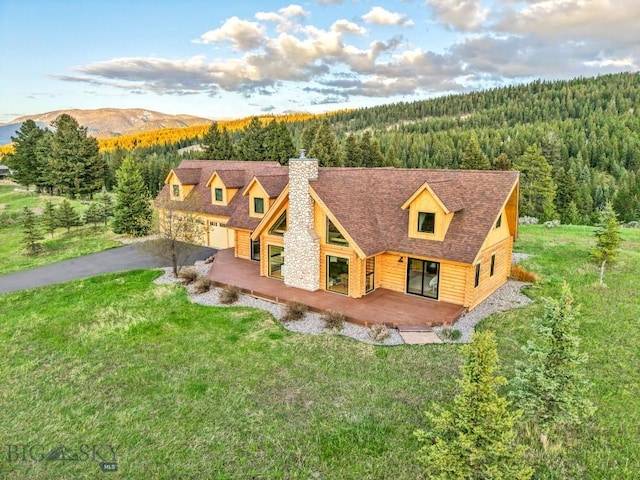 1266 Ousel Falls Rd, Big Sky, MT 59716 - view of front of home with a view of trees, a chimney, a front lawn, and driveway