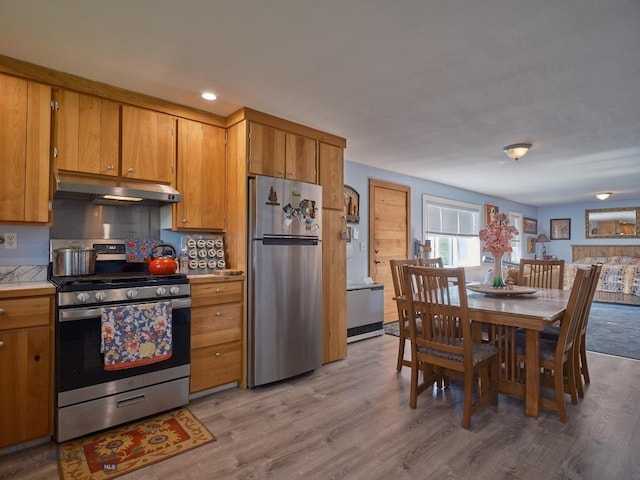 2178 Little Bear Rd, Gallatin Gateway, MT 59730 - kitchen with appliances with stainless steel finishes, under cabinet range hood, brown cabinetry, light wood finished floors, and recessed lighting