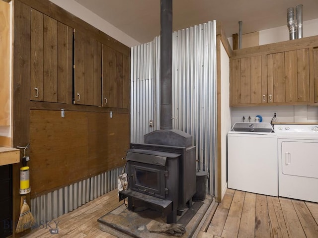2178 Little Bear Rd, Gallatin Gateway, MT 59730 - laundry area with washing machine and clothes dryer, a wood stove, cabinet space, and light wood-style flooring