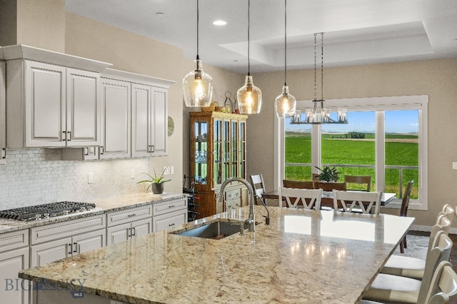 145 Cushing Ln, Manhattan, MT 59741 - kitchen with backsplash, a center island with sink, stainless steel gas cooktop, a sink, and light stone counters