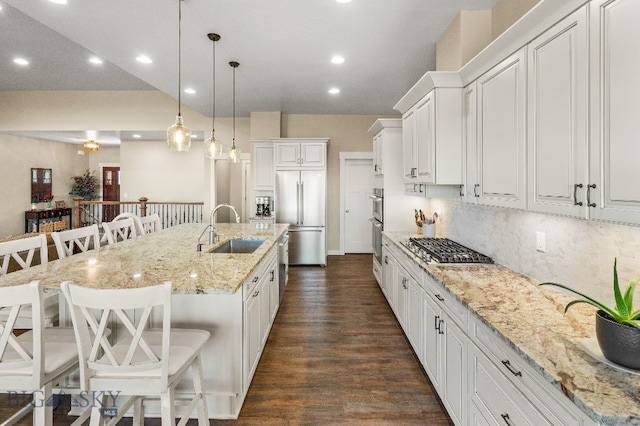 145 Cushing Ln, Manhattan, MT 59741 - kitchen featuring stainless steel appliances, a sink, a breakfast bar, decorative backsplash, and white cabinets