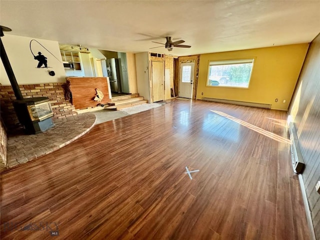 15 S Colorado St, Dillon, MT 59725 - unfurnished living room with baseboard heating, wood finished floors, ceiling fan, and a wood stove
