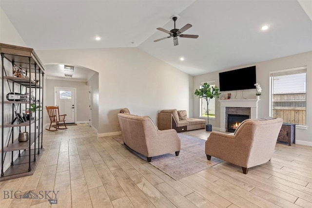 1711 Shelby Ave, Belgrade, MT 59714 - living area featuring arched walkways, light wood-type flooring, ceiling fan, lofted ceiling, and a lit fireplace