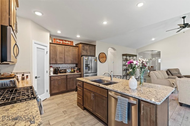 1711 Shelby Ave, Belgrade, MT 59714 - kitchen featuring arched walkways, stainless steel appliances, a sink, open floor plan, and tasteful backsplash