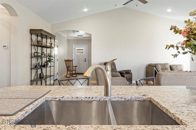 1711 Shelby Ave, Belgrade, MT 59714 - kitchen featuring a sink, vaulted ceiling, a ceiling fan, arched walkways, and light stone counters