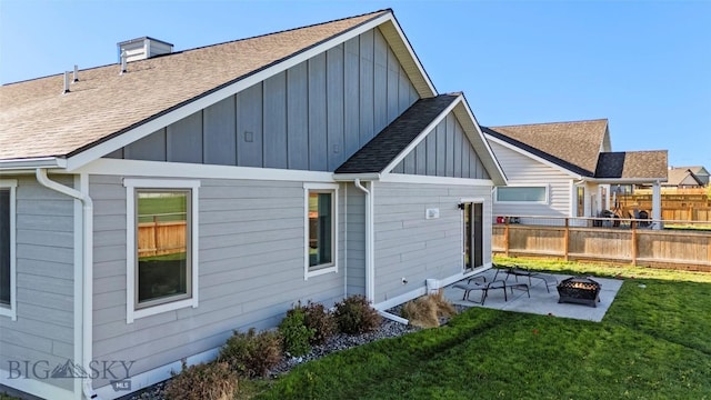 1711 Shelby Ave, Belgrade, MT 59714 - rear view of property with board and batten siding, an outdoor fire pit, a patio, and a shingled roof