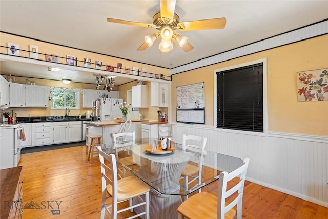 707 Montana St, Belgrade, MT 59714 - dining area with wainscoting, light wood-style floors, and ceiling fan