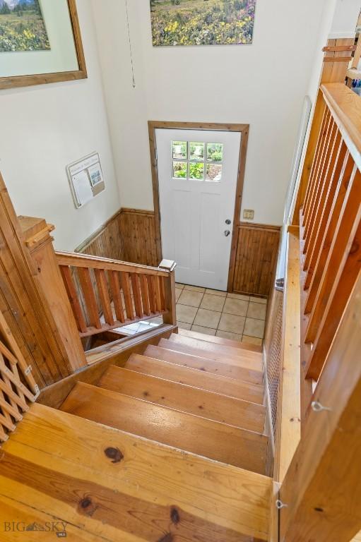 707 Montana St, Belgrade, MT 59714 - foyer entrance featuring wainscoting, stairs, wooden walls, light tile patterned floors, and a towering ceiling
