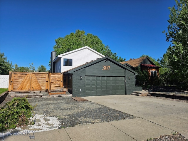 307 Flathead Ave, Bozeman, MT 59718 - view of front of property featuring a gate, an attached garage, concrete driveway, a chimney, and brick siding