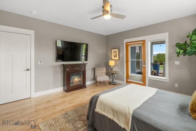 5333 Westmorland Dr, Bozeman, MT 59718 - bedroom with wood finished floors, a glass covered fireplace, baseboards, and a ceiling fan