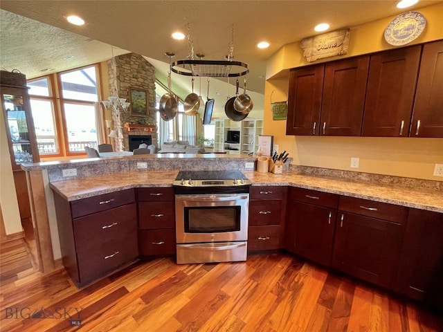 30 Harris Hawk Ct, Dillon, MT 59725 - kitchen featuring stainless steel range with electric stovetop, a peninsula, light wood-type flooring, a fireplace, and lofted ceiling
