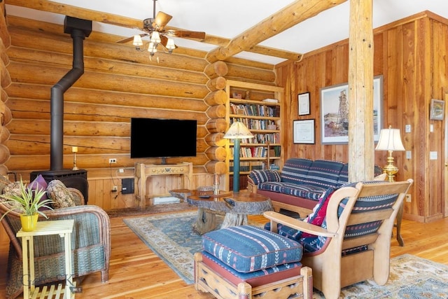 23 Lake Trl, Cameron, MT 59720 - living room featuring wood finished floors, a wood stove, a ceiling fan, beamed ceiling, and rustic walls