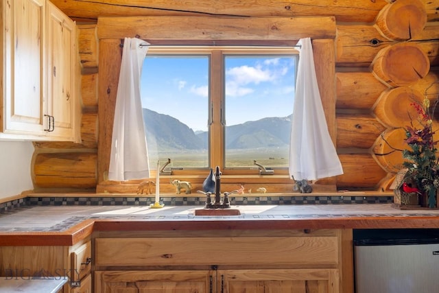 23 Lake Trl, Cameron, MT 59720 - kitchen view of log walls, tile countertops, a mountainous background, a sink, and dishwashing machine