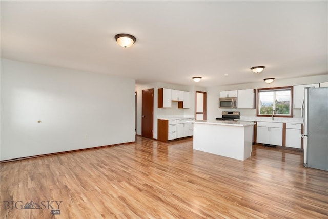 413 S Oak St, Townsend, MT 59752 - kitchen with stainless steel appliances, white cabinetry, light countertops, light wood-style floors, and a kitchen island
