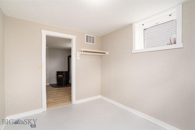 413 S Oak St, Townsend, MT 59752 - unfurnished bedroom with a wood stove, baseboards, and concrete floors