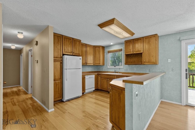 416 Morrow St, Bozeman, MT 59715 - kitchen with white appliances, a peninsula, brown cabinets, a textured ceiling, and light wood finished floors