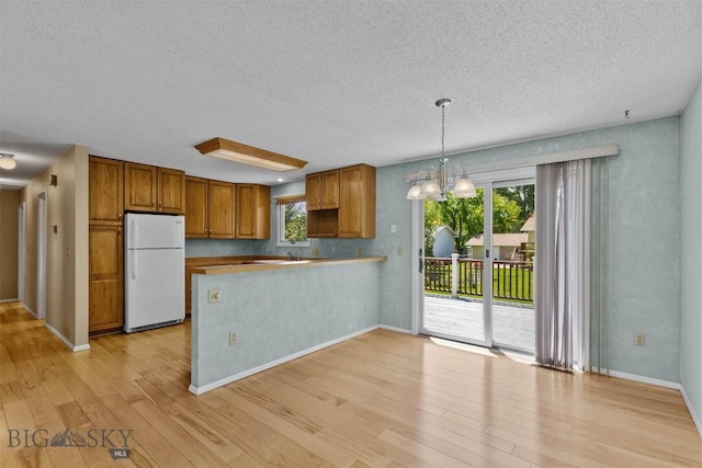 416 Morrow St, Bozeman, MT 59715 - kitchen featuring freestanding refrigerator, a textured ceiling, light wood-style flooring, a peninsula, and healthy amount of natural light