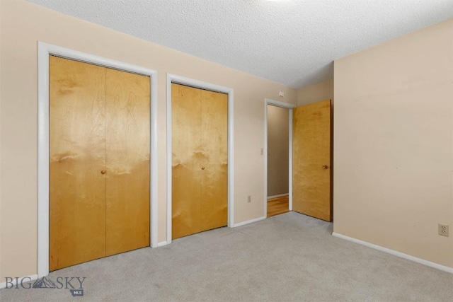 416 Morrow St, Bozeman, MT 59715 - unfurnished bedroom with two closets, carpet flooring, baseboards, and a textured ceiling