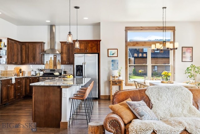 2296 Boylan Rd, Bozeman, MT 59715 - kitchen featuring stainless steel appliances, wall chimney range hood, open floor plan, a breakfast bar area, and dark wood finished floors