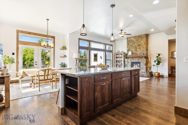 2296 Boylan Rd, Bozeman, MT 59715 - kitchen with open shelves, a ceiling fan, dark wood-type flooring, dark brown cabinets, and a stone fireplace