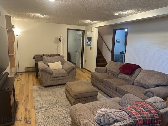 305 Mcewen Dr, Belgrade, MT 59714 - living area featuring a textured ceiling, wood finished floors, stairway, and a baseboard heating unit