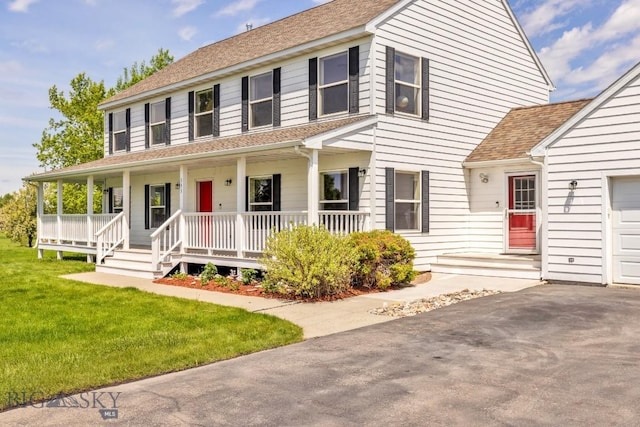 193 Lucille Ln, Bozeman, MT 59718 - colonial house featuring covered porch, roof with shingles, a front lawn, asphalt driveway, and an attached garage